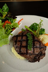 A delicious grilled steak is served with a side of mixed salad and vegetables on a plate