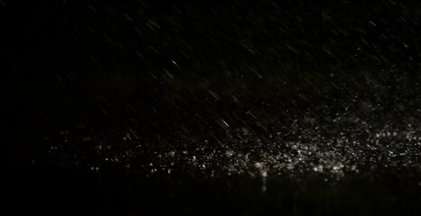 Dark moody rain droplets falling in night light, cinematic abstract texture perfect for background, drama, mystery, and creative design projects, symbolizing solitude and depth