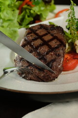 Delicious grilled steak being sliced on a plate, served with a fresh salad