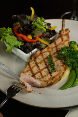 Delicious grilled pork chop with a variety of fresh side dishes