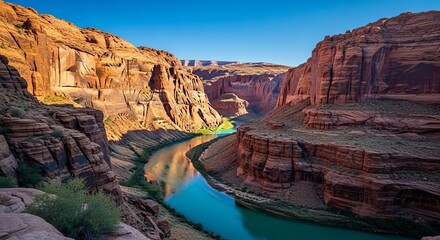 Majestic colorado river winds through towering red rock canyon walls under a clear blue sky