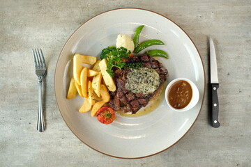 Delicious grilled steak served on a plate with vegetables and sides. The meal includes a steak, french fries, vegetables, and sauce