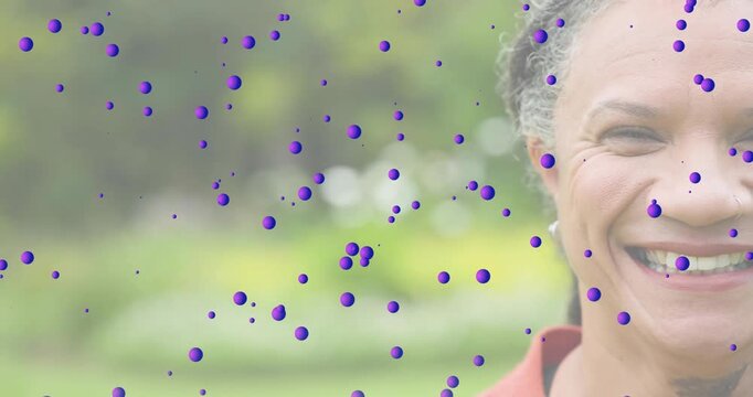 Mature woman brightening eyes as purple spheres scattering across face overlay in technology demo - Powered by Adobe