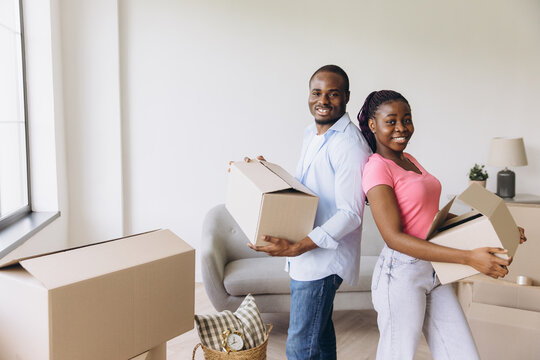 African couple moving to new home carrying boxes