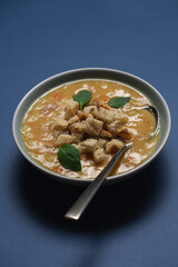 Seasonal hot pea soup with croutons on minimalist blue background, healthy homemade comfort food top view