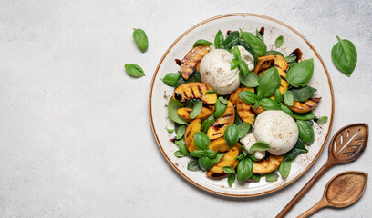 Mediterranean salad with burrata cheese, grilled peaches, fresh basil leaves, olive oil and balsamic glaze, gourmet summer dish on light background