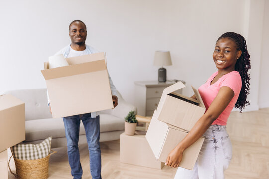African American couple moving into new home carrying boxes - Powered by Adobe