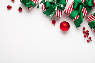Merry Christmas and Happy Holidays greeting card, frame, banner. New Year. Red green Christmas decoration and gifts, presents on white background top view. Xmas holiday festive theme.