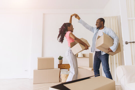 Happy African couple dancing carrying moving day boxes