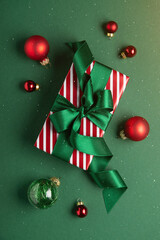 Merry Christmas and Happy Holidays greeting card, frame, banner. New Year. Red Christmas ornaments and gifts, presents on green background top view. Xmas holiday festive theme. Christmas decoration