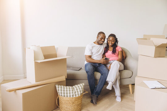 African couple moving to new home using smartphone