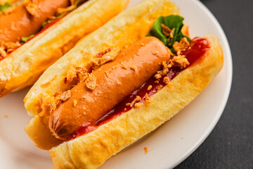 Hotdog fried onions, sausage, bun, sauce fast food tasty snack fresh delicious gourmet food background on the table rustic top view copy space
