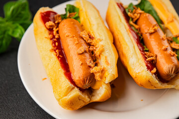Hotdog fried onions, sausage, bun, sauce fast food tasty snack fresh delicious gourmet food background on the table rustic top view copy space