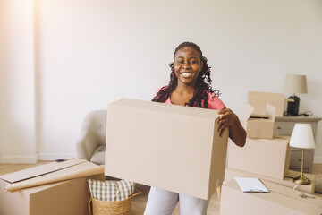 Happy African woman relocating, unpacking in new apartment