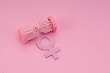 Hourglass with the female gender symbol. Women's health, menopause concept.