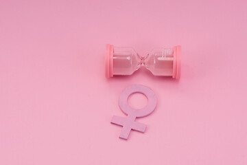 Hourglass with the female gender symbol. Women's health, menopause concept.