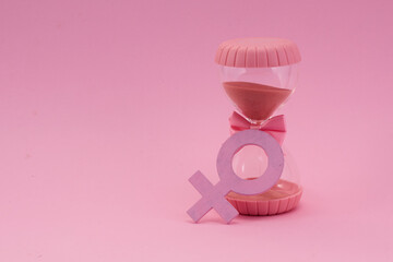 Hourglass with the female gender symbol. Women's health, menopause concept.