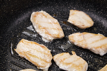Grilled chicken fillets sizzling in a frying pan, showcasing golden-brown grill marks and juicy texture, highlighting the cooking process and culinary art