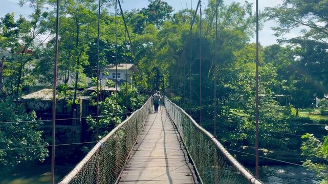 People crossing suspenssion bridge over the river in Bukit Lawang, North Sumatra Indonesia
