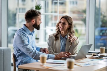 Business colleagues collaborating on laptop in office meeting