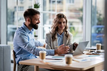 Business colleagues collaborating on laptop in office meeting