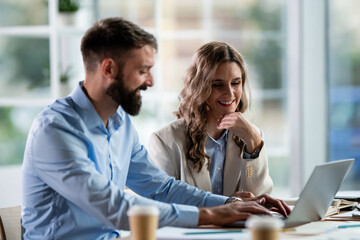 Business colleagues collaborating on laptop in office meeting
