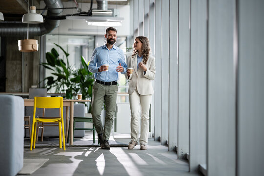 Business colleagues walking and talking during coffee break