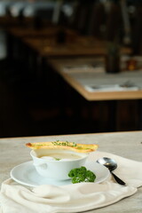 A delectable soup served with a breadstick and fresh garnish on a white plate in restaurant