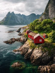 Papier peint photo Villes / Voyage Red cabins perch on a rocky coast  majestic mountains loom in the background  © Abdi