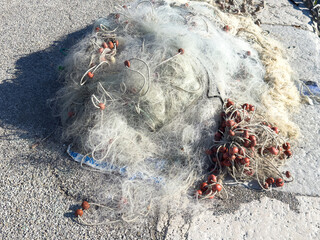 Tangled fishing nets on sunlit concrete surface with red floats