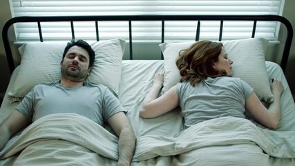 Man with insomnia lying awake in bed next to his sleeping partner