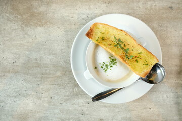 Delicious bowl of creamy soup topped with a piece of garlic bread and a spoon