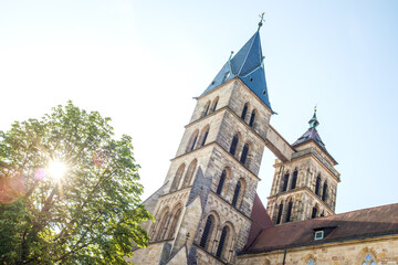 Untersicht Stadtkirche St. Dionys in Esslingen am Neckar
mit Laubbaum im Gegenlicht.