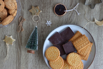 Various Christmas decorations, cookies, chocolate and nuts on wooden background. Flat lay.