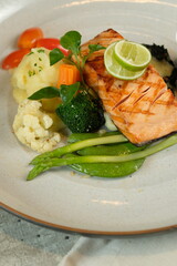 Grilled salmon served on a plate with various vegetables and garnish