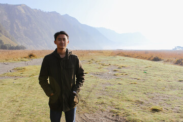 Asian Young Male Hiker Standing in Misty Mountain Valley Landscape. Depicting solitude, travel, and natural beauty.