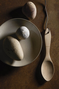 assiette et  galets , cuill&egrave;re en bois , esprit des lieux , table en m&eacute;tal  rouill&eacute;  , nature morte fiction ,