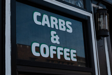 Shop sign showcasing carbs and coffee in a cozy cafe setting on a sunny day