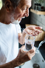 Senior man taking medication at home