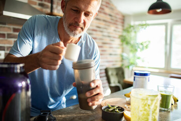 Mature man preparing a protein shake at home