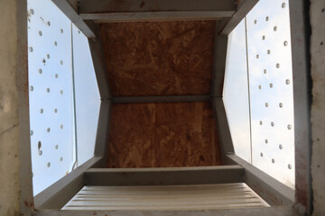 Architectural close-up view of a modern metal and wood ceiling structure with geometric design and...