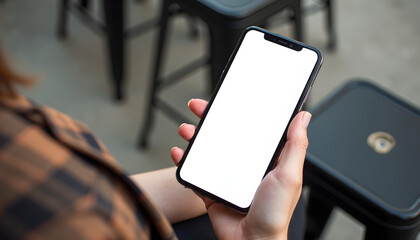 Woman holding a smartphone with a blank white screen in a cafe setting