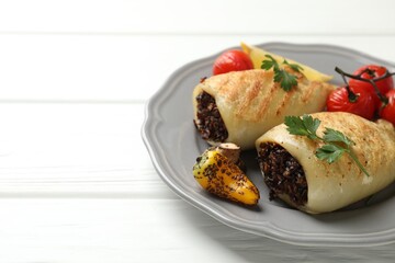 Pieces of tasty grilled squid stuffed with mushrooms, parsley and vegetables on white wooden table, closeup. Space for text