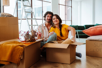 Happy young couple relocating in a new apartment. Young woman and man working and arranging the new...