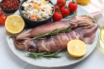 Raw squids, stuffing, rosemary, lemon and tomatoes on white tiled table, closeup