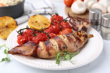 Tasty stuffed squid, microgreens, lemon and tomatoes on white tiled table, closeup