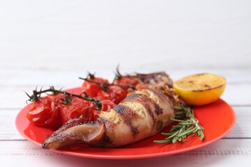 Tasty stuffed squid, rosemary, lemon and tomatoes on light wooden table, closeup