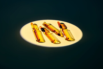Several ampoules in the spotlight on a beige background.
