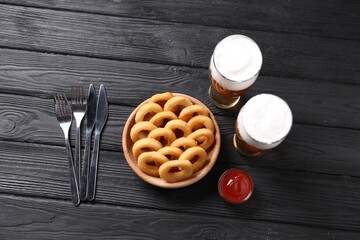 Fried squid rings with sauce and beer served on black wooden table, flat lay