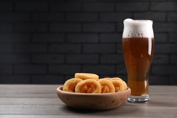 Fried squid rings and beer served on wooden table. Space for text